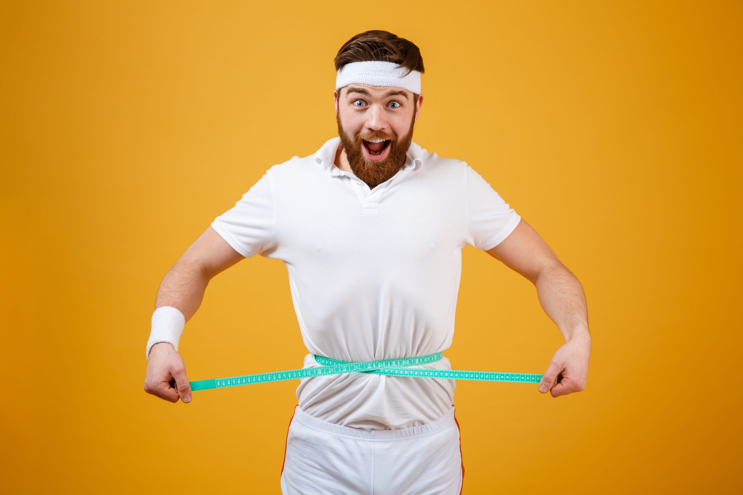 Smiling man measuring his waist with a tape